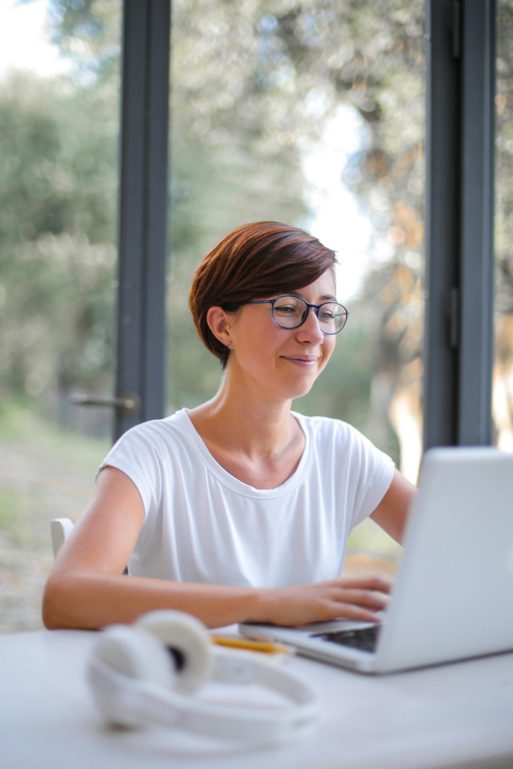 A happy woman with short hair using a laptop indoors, showcasing remote work lifestyle.